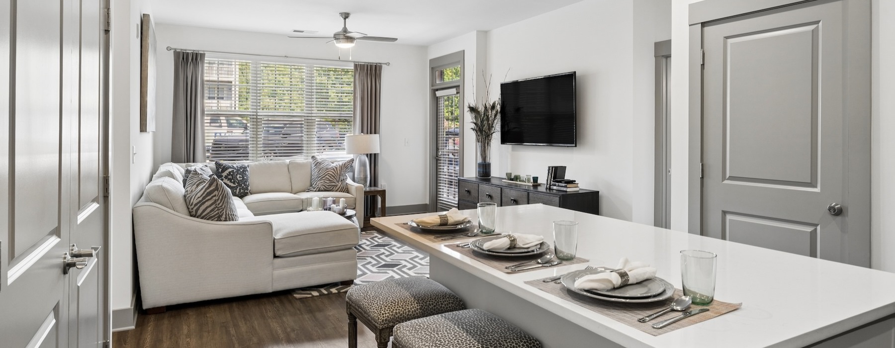 a kitchen and a living room with a couch, tv and chairs
